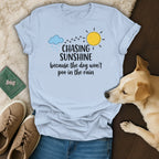 Light blue t-shirt with "Chasing Sunshine because the dog won't poo in the rain" text.