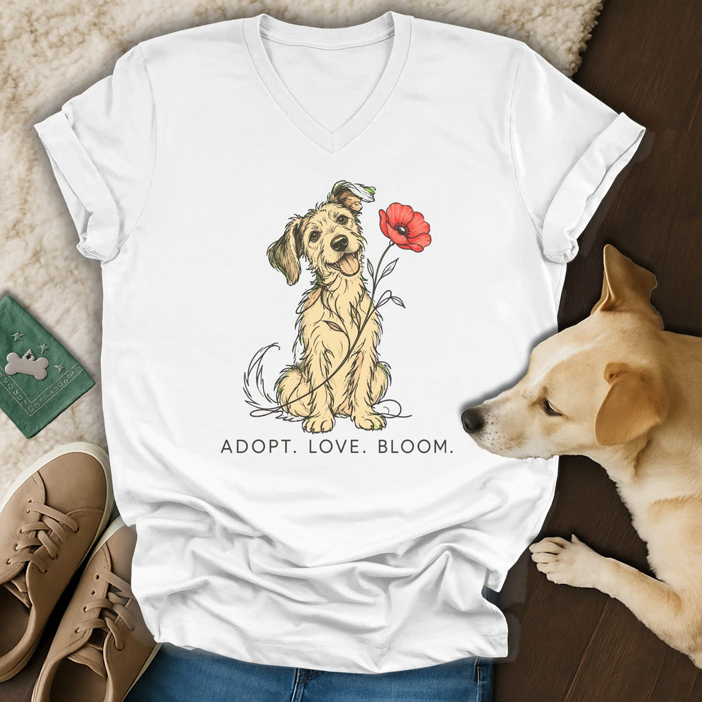 A white V-neck t-shirt featuring a cartoon dog holding a red poppy and the text ADOPT. LOVE. BLOOM.