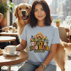 A woman wearing a light blue t-shirt with a Dirt and Dog Hair Club graphic while seated with a dog.