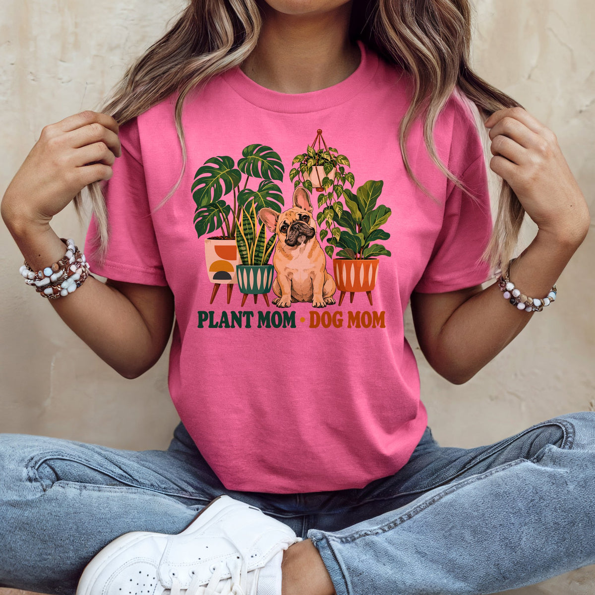 A woman wearing a pink t-shirt featuring a French bulldog surrounded by potted plants and the text PLANT MOM DOG MOM.