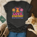 Dark grey t-shirt with a happy dog and flowers graphic reading "LOVE EVERYBODY Okay, mostly dogs."