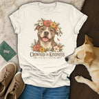 A cream-colored t-shirt with a graphic of a pit bull wearing a flower crown and the text "Crowned in Kindness".