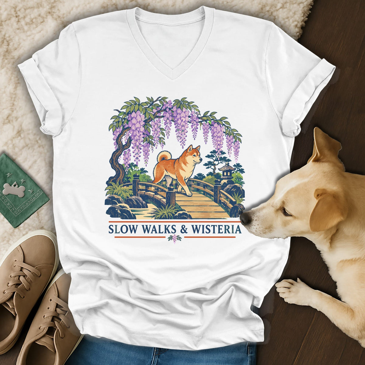 White V-neck t-shirt featuring an illustration of a Shiba Inu on a bridge beneath wisteria, with text reading Slow Walks & Wisteria.