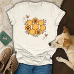 White t-shirt with a honeycomb paw print design, bees, flowers, blue jeans, shoes, and a dog.