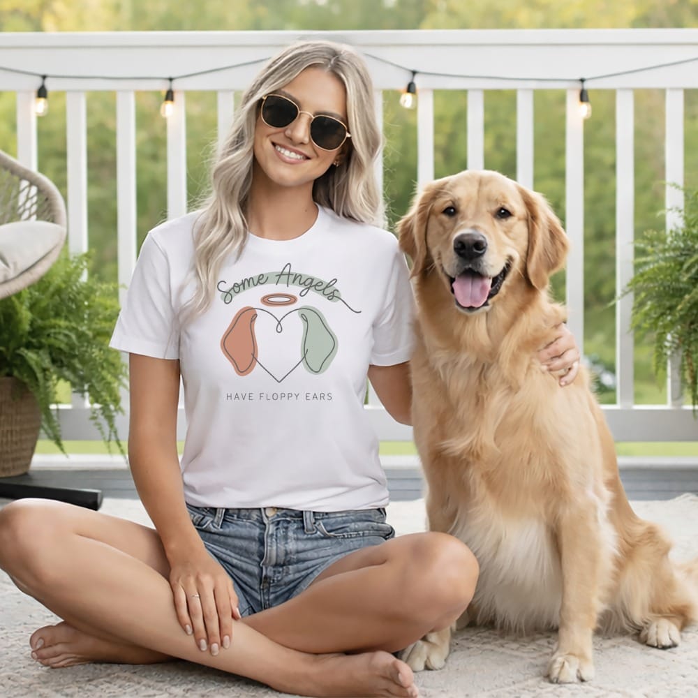 Woman in white t-shirt with "Some Angels Have Floppy Ears" graphic and golden retriever.