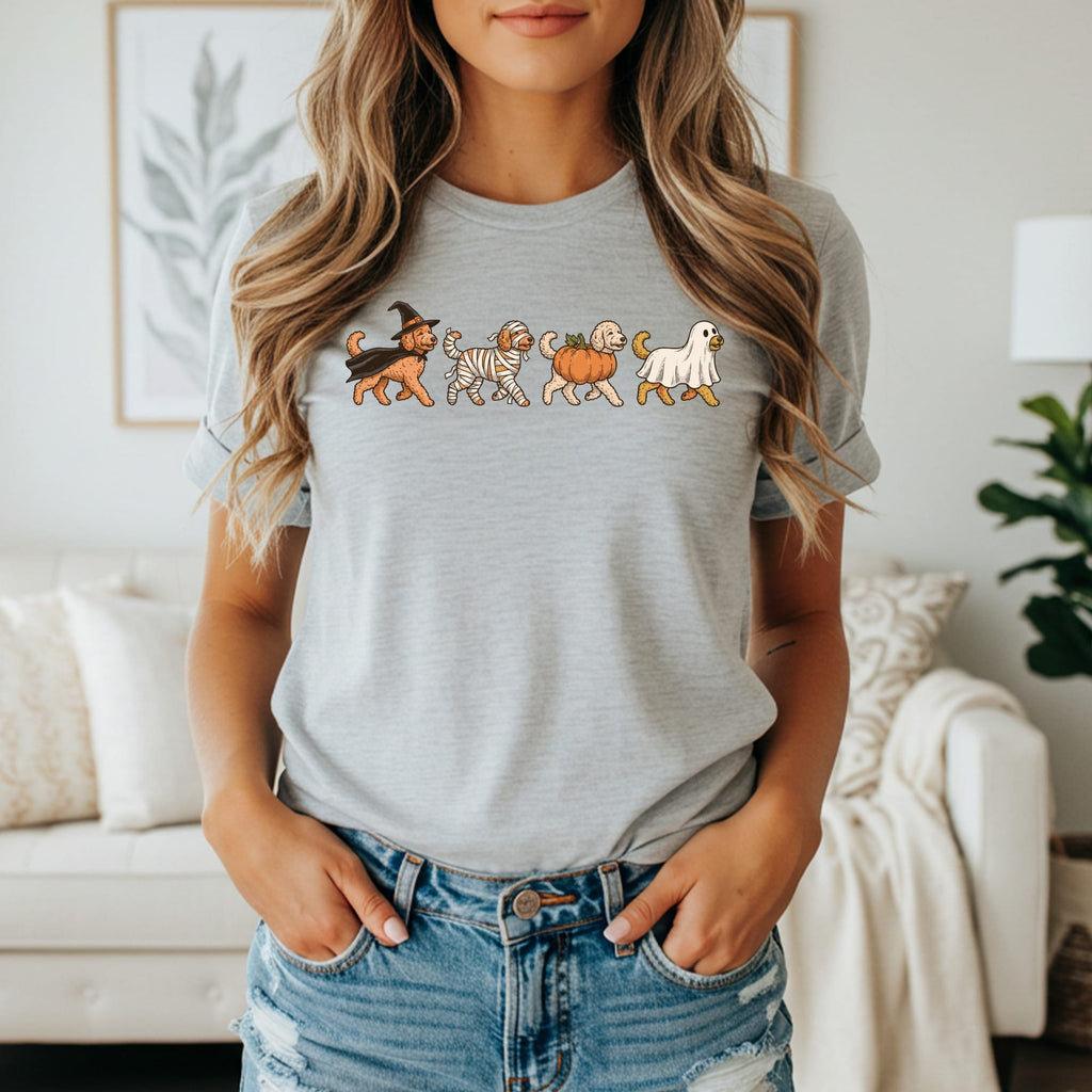 Four dogs dressed in Halloween costumes walk in a line across a grey t-shirt.