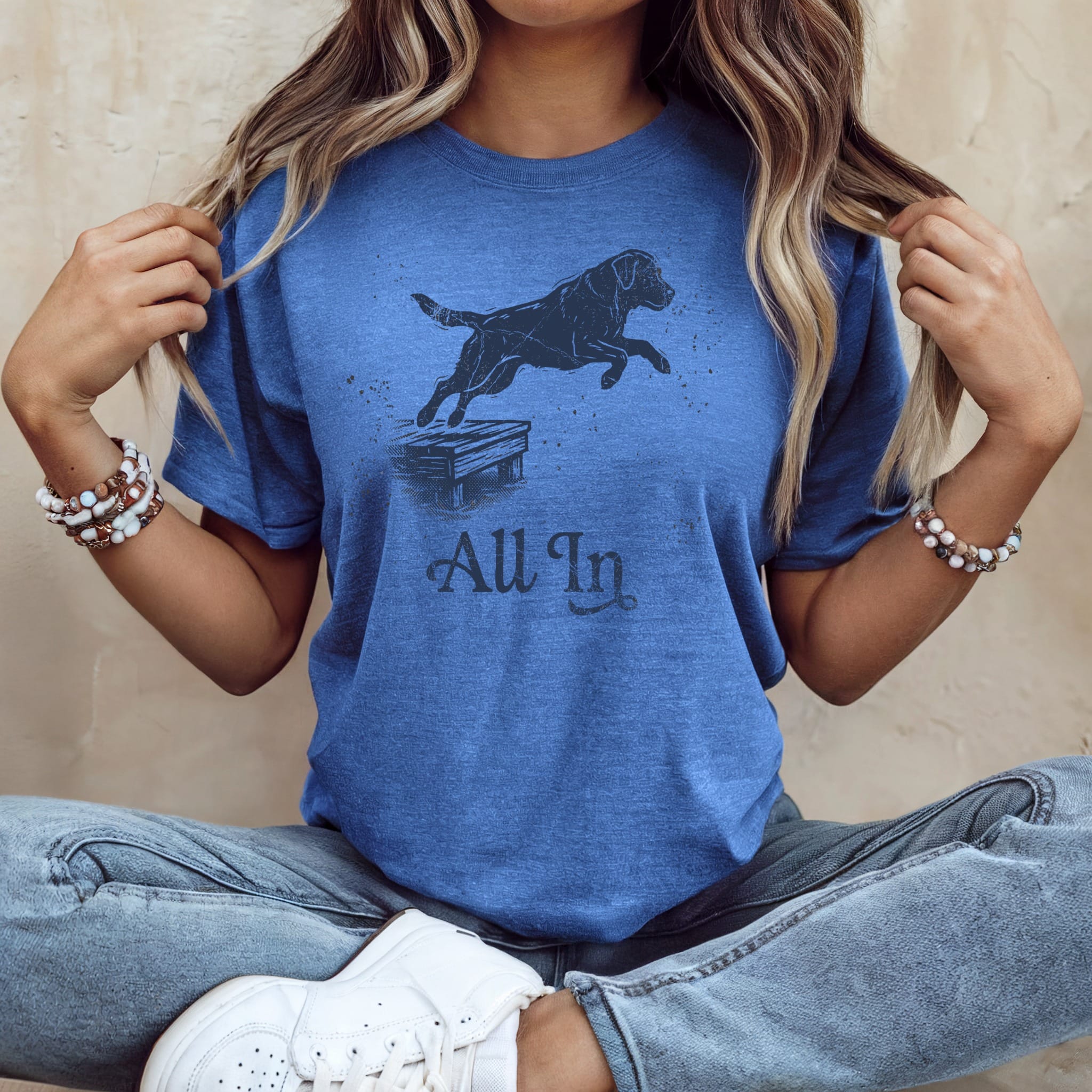 Blue t-shirt with black dog jumping over obstacle, "All In" text.