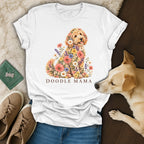 A white t-shirt featuring a goldendoodle made of flowers and the text Doodle Mama, placed among casual accessories.