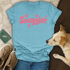 Light blue t-shirt with "Snuggler" in pink lettering and paw prints.