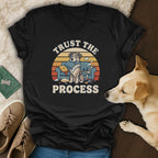 Black t-shirt with "Trust the Process" and cartoon dogs on a messy couch.
