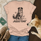 Peach t-shirt with a black ink drawing of an Australian Shepherd and the text "Aussie-Tumn".