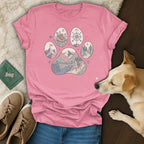 Pink t-shirt with a paw print graphic featuring mountain, bridge, dog, and compass designs.