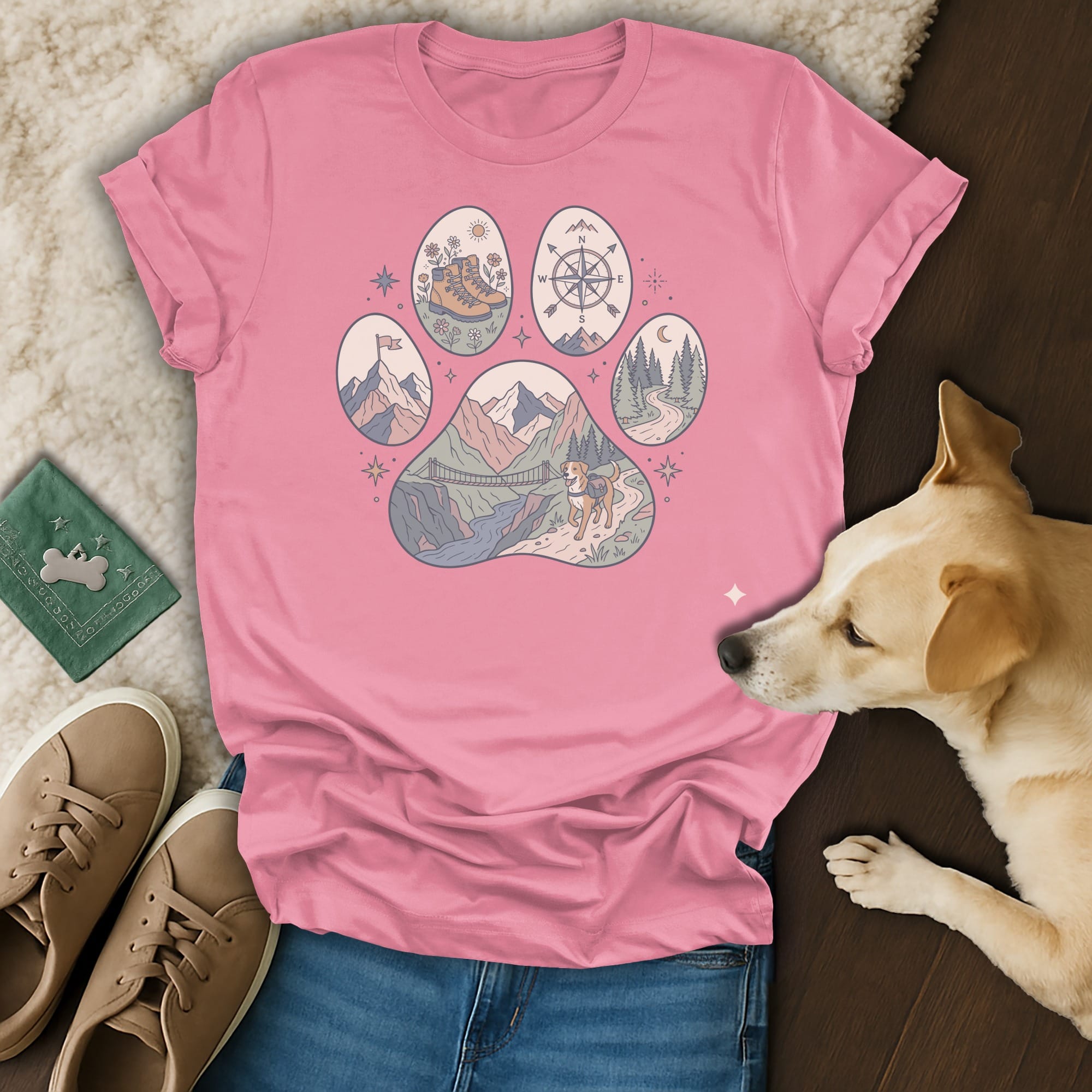 Pink t-shirt with a paw print graphic featuring mountain, bridge, dog, and compass designs.