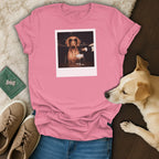 Pink t-shirt with a graphic of a dog in sunglasses being poured champagne.