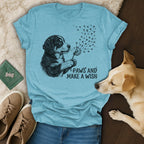 Light blue t-shirt with dog blowing dandelion seeds, "Paws and Make a Wish" text.