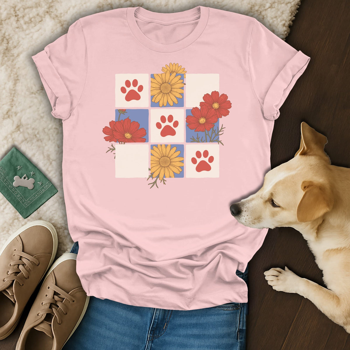 Pink t-shirt with a grid of red paw prints and colorful flowers.