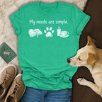 Green t-shirt with "My needs are simple" and graphics of a book, paw, candle, and teacup.