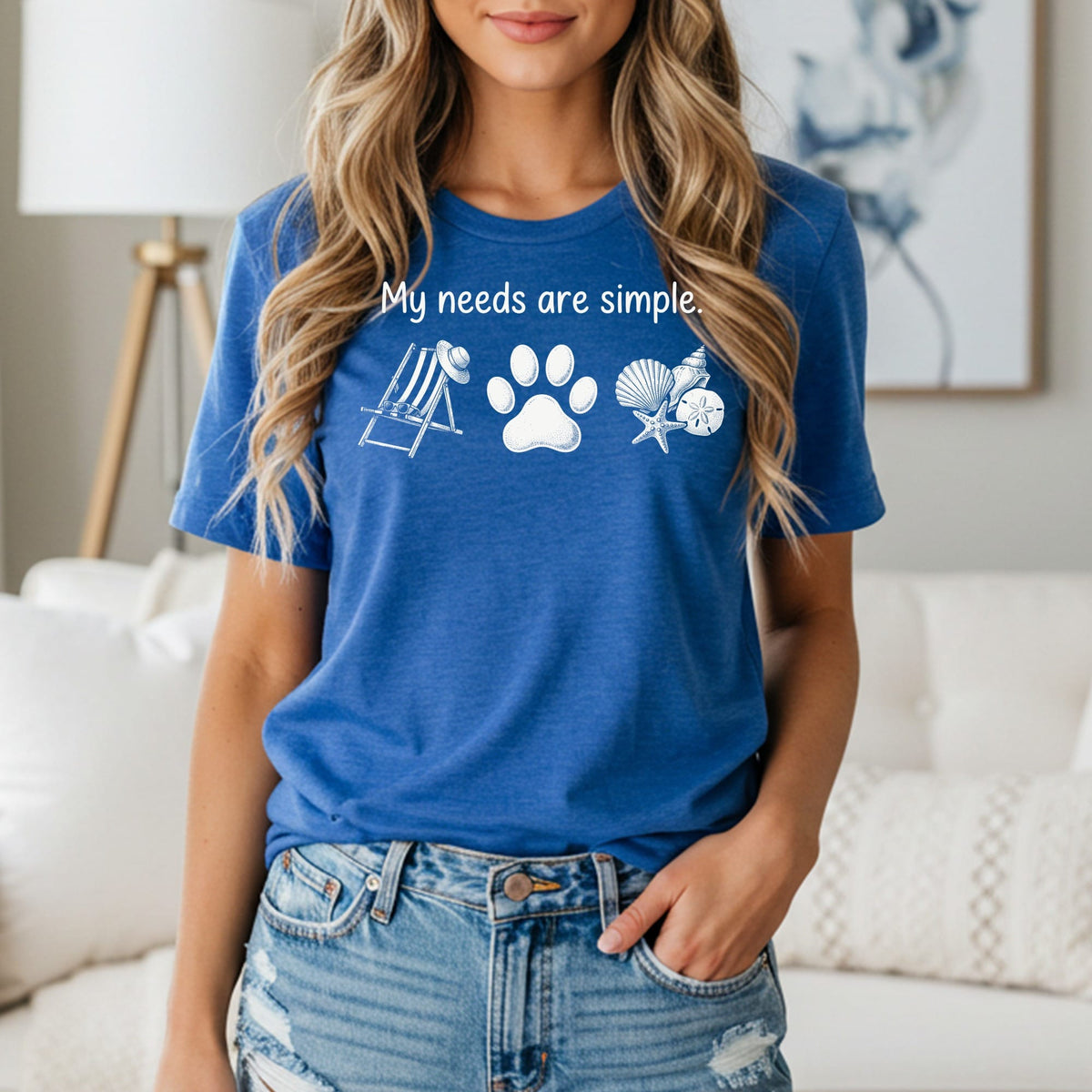 Blue t-shirt with "My needs are simple." text and paw print, beach chair, seashells.