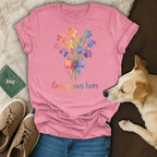 Pink t-shirt with watercolor paw print bouquet and "love grows here" text.