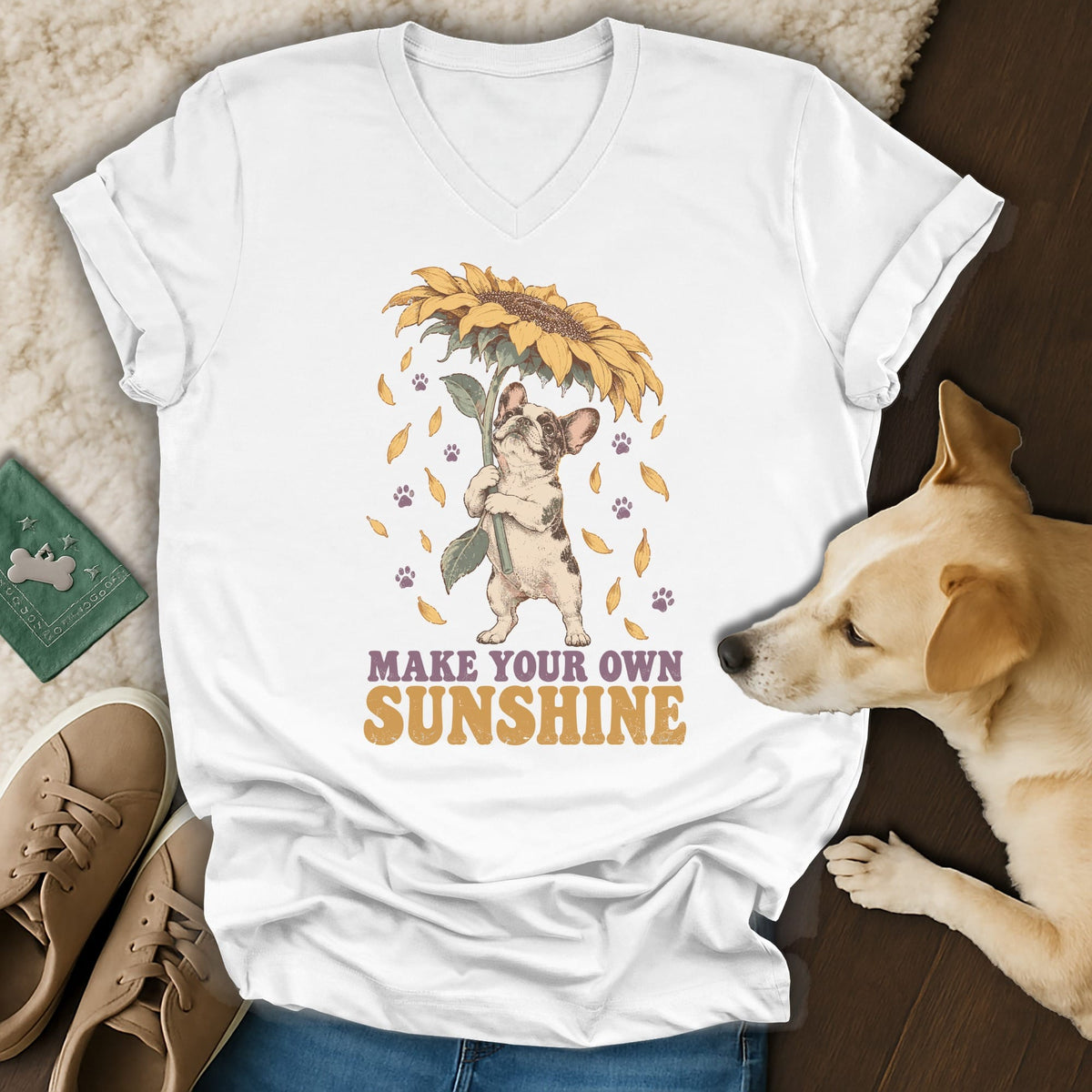 A white V-neck t-shirt featuring a graphic of a French bulldog holding a sunflower and the text Make Your Own Sunshine.