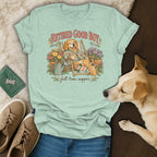 Light green t-shirt with a vintage graphic of a golden retriever relaxing in a deck chair, surrounded by flowers.