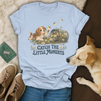 Light blue t-shirt featuring a puppy and bees graphic, laid flat with jeans and sneakers.