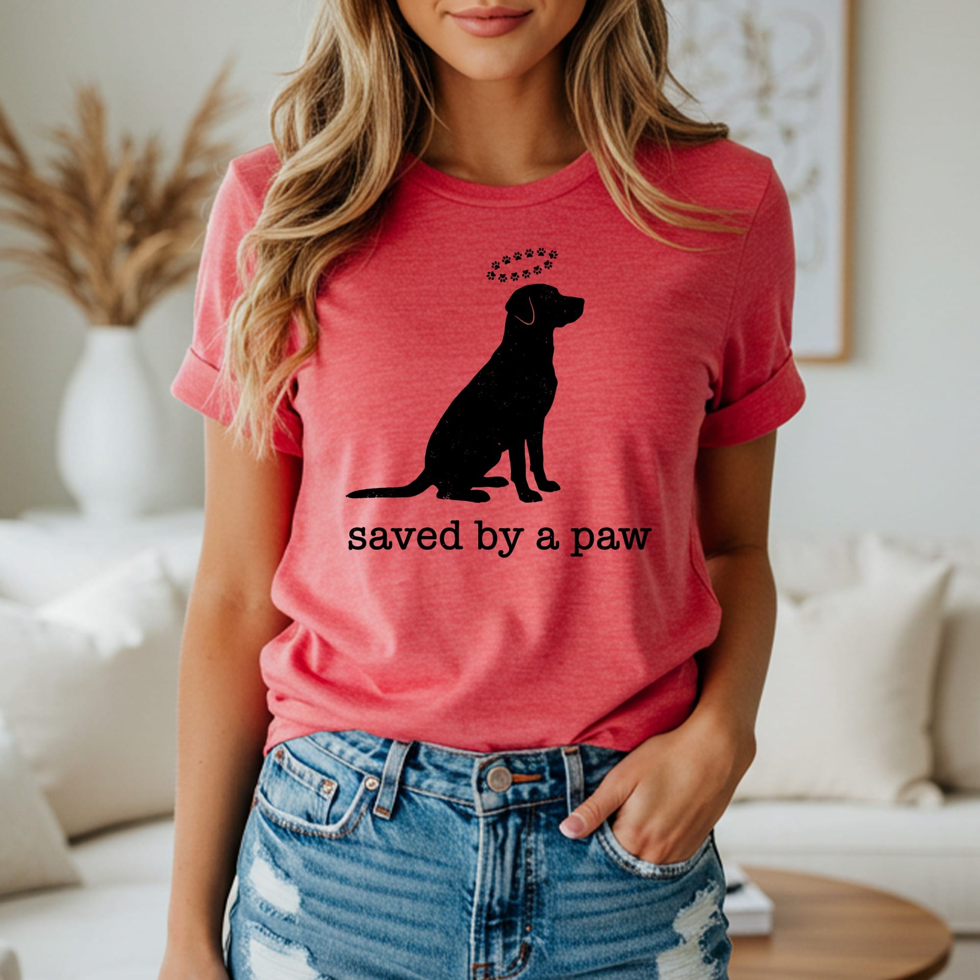 T-shirt with silhouette of a sitting dog and text "saved by a paw".