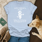 Light blue t-shirt with graphic of dog holding wine and coffee, text reads "Coffee's supposed to go first. Today wine cut the line. I'm staying OUT OF IT"