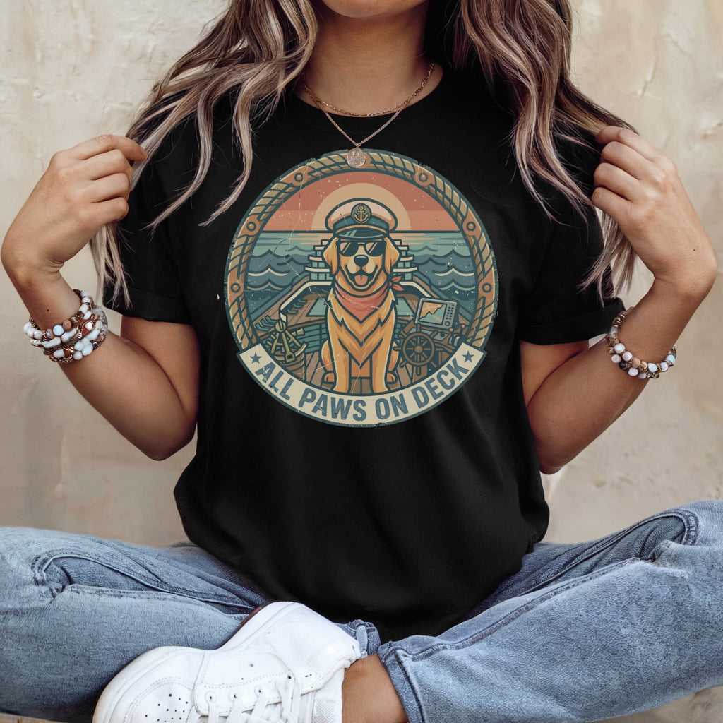 Black t-shirt with a circular nautical graphic featuring a dog wearing a captain's hat, text reads "ALL PAWS ON DECK."