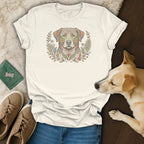 Cream t-shirt with a colorful, floral dog graphic, laid flat with jeans and shoes.