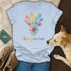 Light blue t-shirt with rainbow paw print bouquet and text "love grows here".