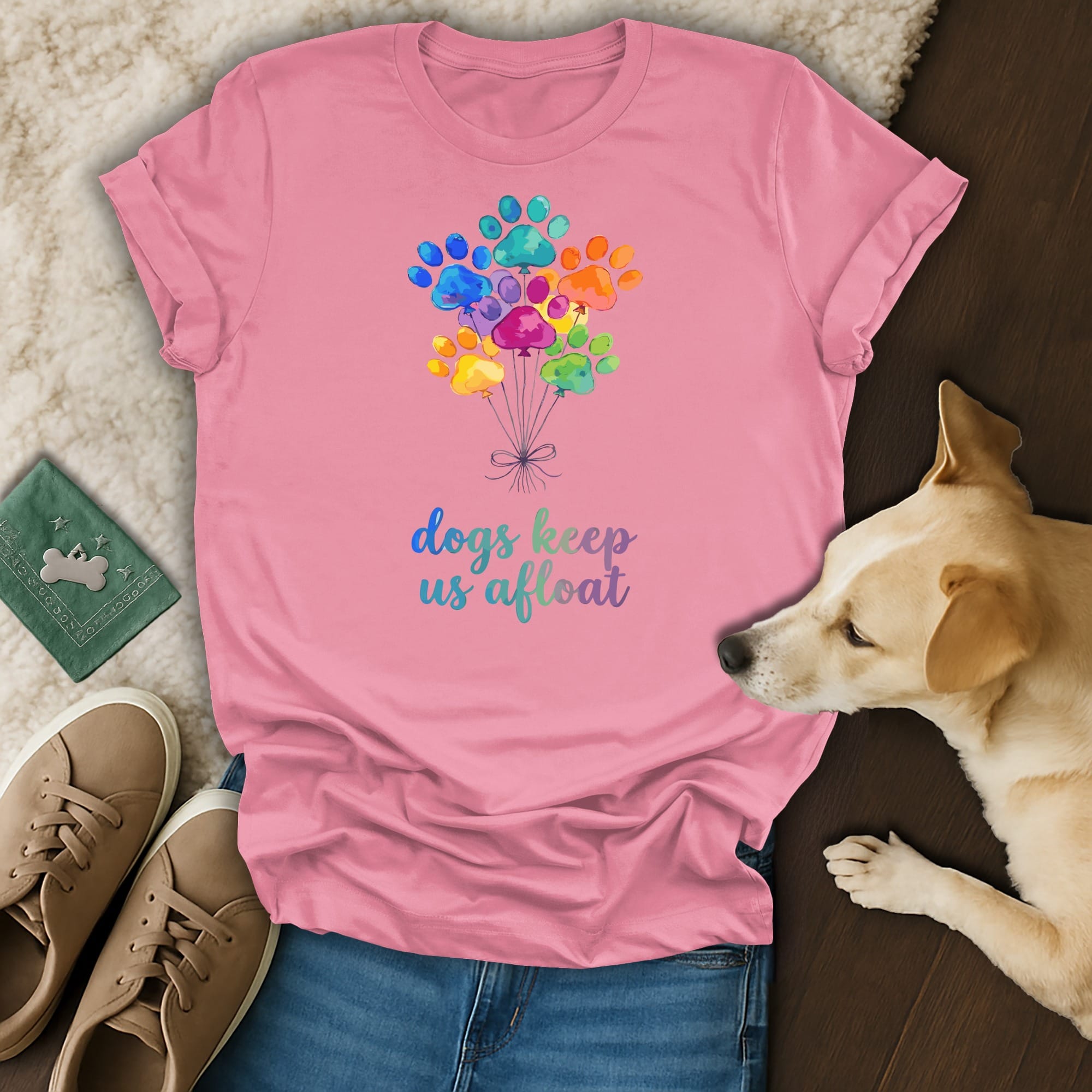 Pink t-shirt with colorful paw print balloons and text "dogs keep us afloat".