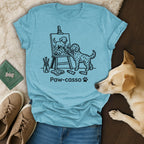 T-shirt with a doodle dog painting another dog at an easel, text "Paw-casso".