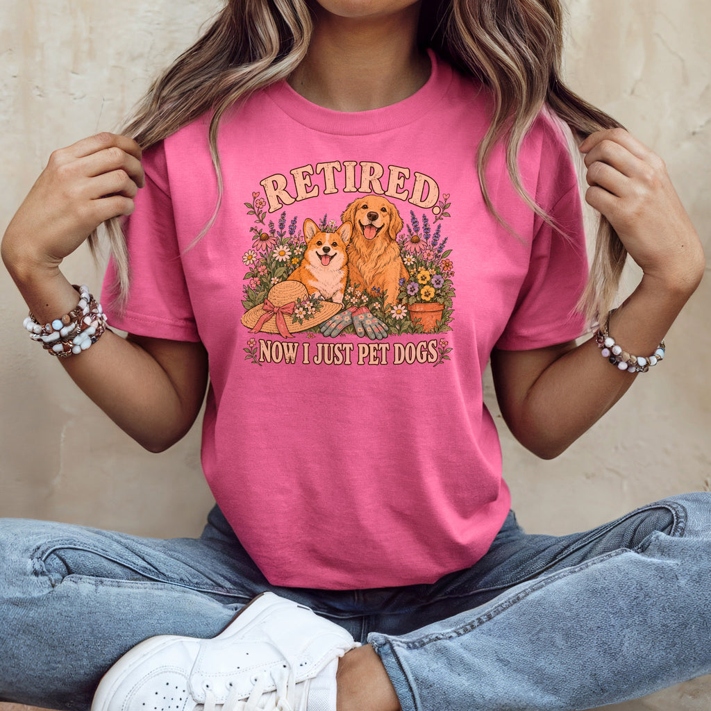 A person wears a pink t-shirt with a graphic of two dogs and the text Retired Now I Just Pet Dogs.