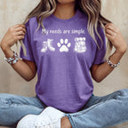 Purple t-shirt with "My needs are simple." and hiking icons: boots, paw print, backpack.