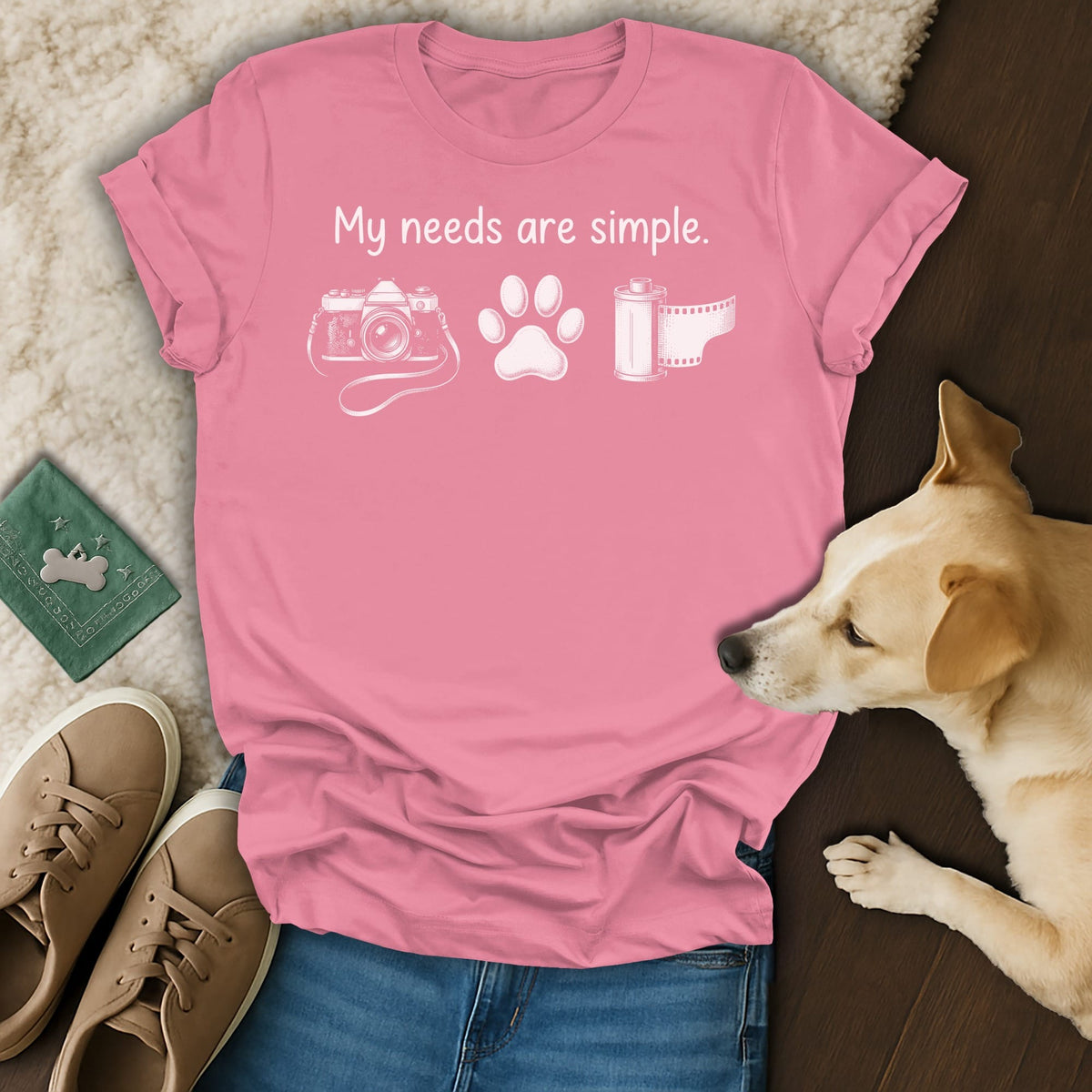 Pink t-shirt with "My needs are simple" and icons of camera, paw print, and film.