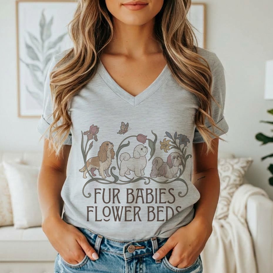 A person wearing a grey v-neck t-shirt featuring a graphic of three dogs, flowers, and the text Fur Babies Flower Beds.
