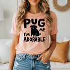 Peach t-shirt with black text and pug graphic reading "Pug me I'm adorable".