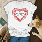 White t-shirt with red paw prints forming a heart and text "all you need is love and a dog."