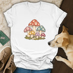 A white V-neck t-shirt featuring a colorful mushroom graphic with paw print patterns, laid out near a dog.