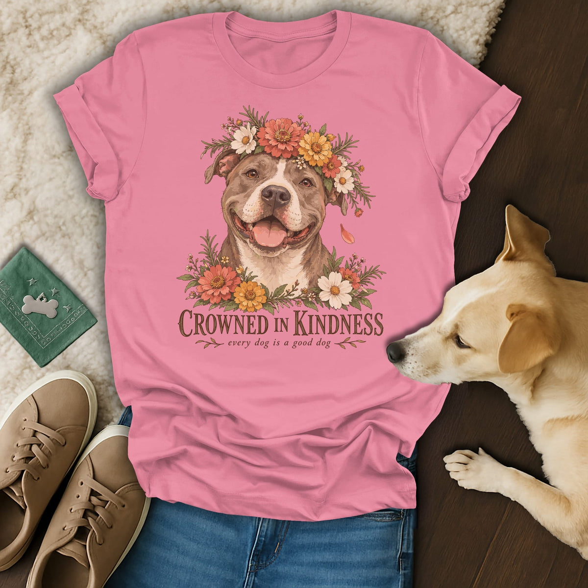 A pink t-shirt with a graphic of a pit bull wearing a flower crown and text reading "Crowned in Kindness."