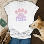 White t-shirt with "Bestie" text inside a paw print design, faded pink and purple.