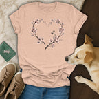 Peach t-shirt with floral heart design made of paw prints, shown with jeans, sneakers, and a dog.