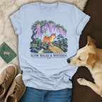 Light blue t-shirt featuring a Shiba Inu on a bridge beneath wisteria, with "SLOW WALKS & WISTERIA" text.