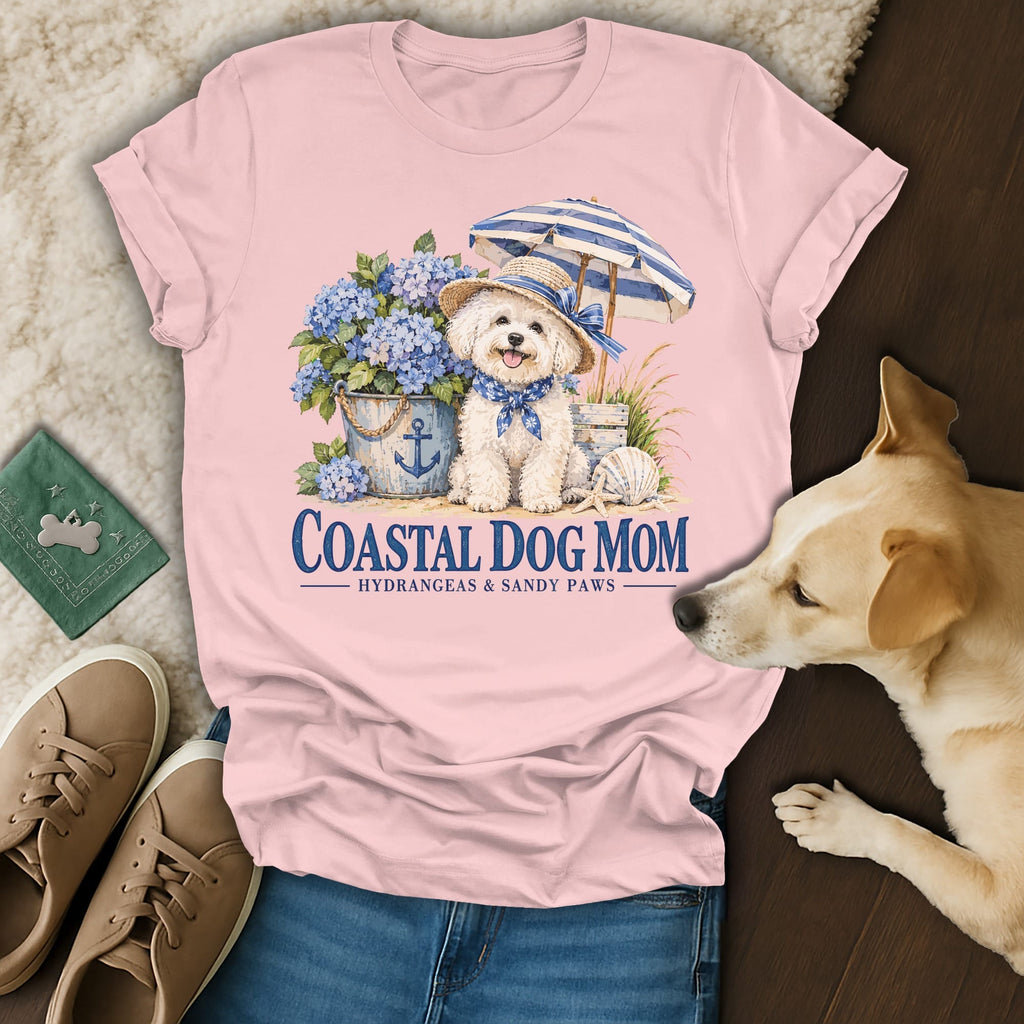 Pink short-sleeve t-shirt featuring a graphic of a white dog wearing a hat and bandana, with text reading Coastal Dog Mom.