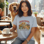 A woman wearing a light blue t-shirt with a golden retriever graphic sits at a café table next to a golden retriever.