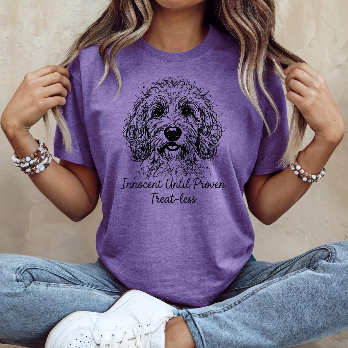 Purple t-shirt with a black line drawing of a dog and text "Innocent Until Proven Treat-less".