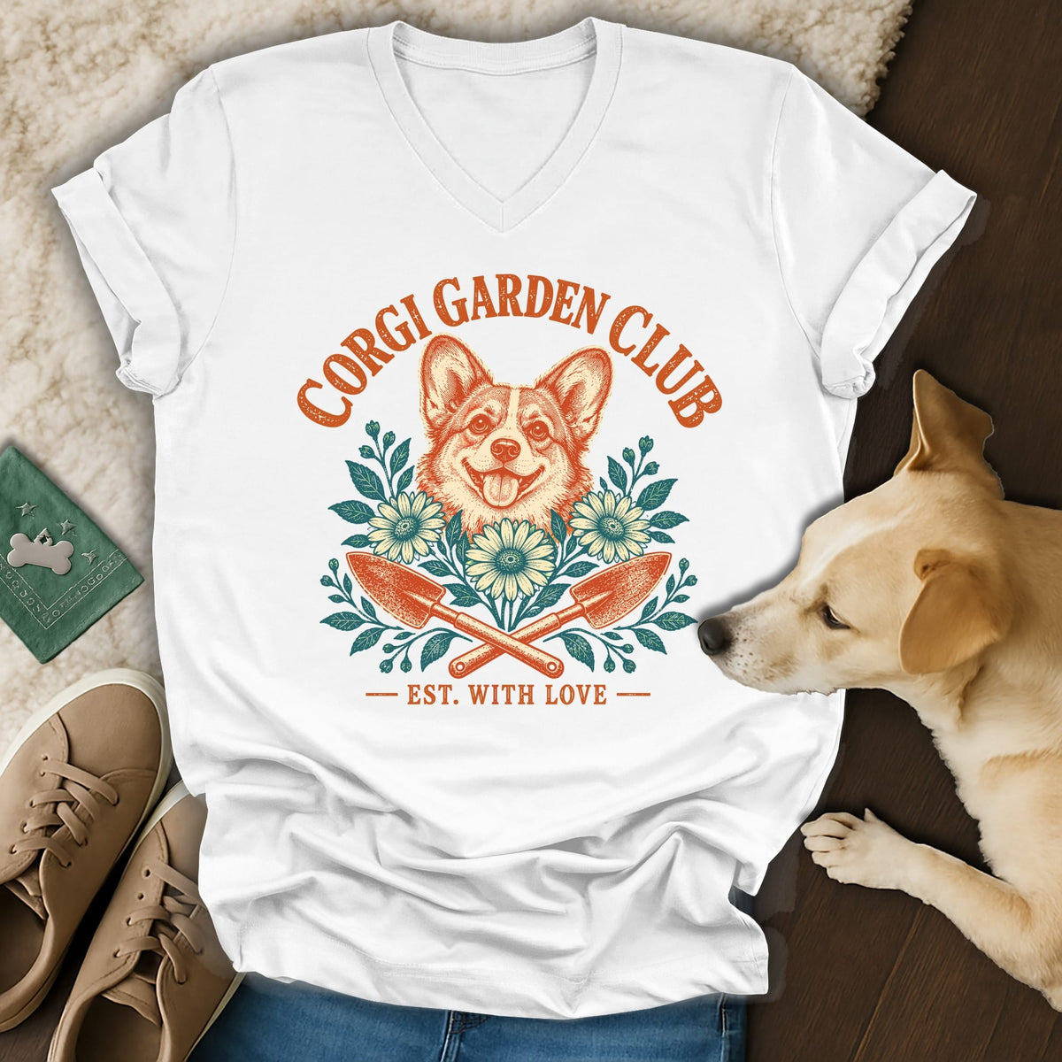 White v-neck t-shirt featuring a Corgi Garden Club graphic with flowers, trowels, and a dog's head.