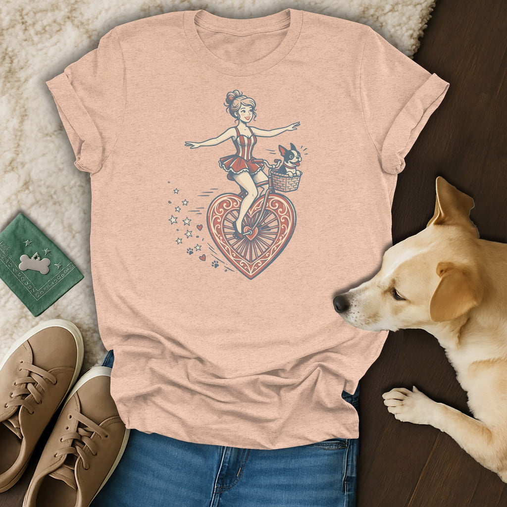 T-shirt with a whimsical illustration of a woman on a heart-shaped bicycle with a dog in the basket.