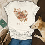 Cream t-shirt with heart floral design, dog silhouette, and "fall in love" text.
